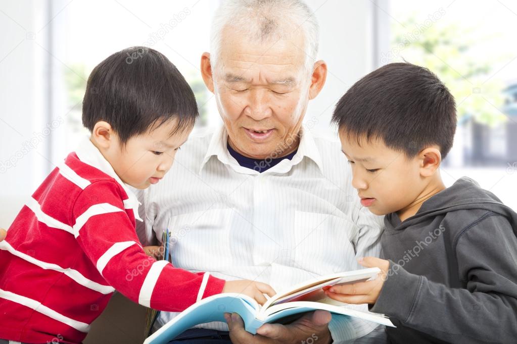 grandfather and grandchildren reading a book