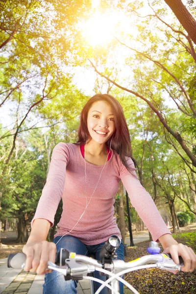 Jovem mulher andar de bicicleta e ouvir música na trilha da floresta — Fotografia de Stock