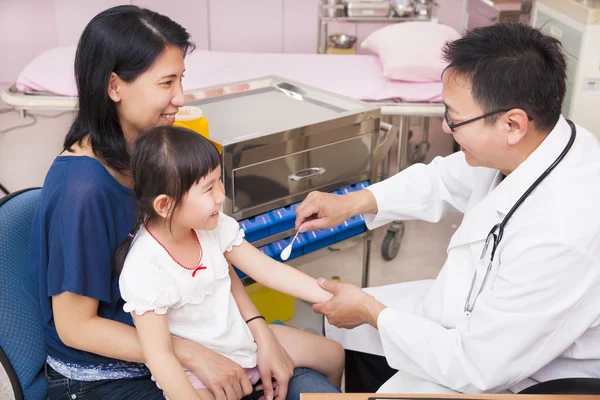 Pediatrician rubbing medication on little girl arm wound — Stock Photo, Image