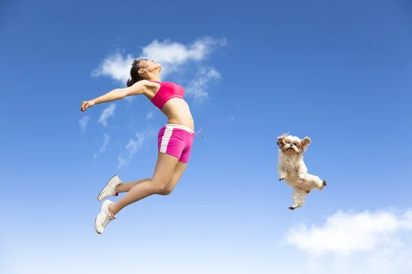 Genç kadın ve köpek gökyüzüne jumping — Stok fotoğraf