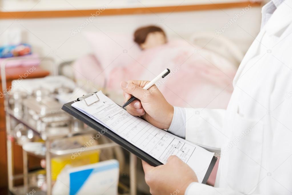 doctor writing on a medical chart with patient