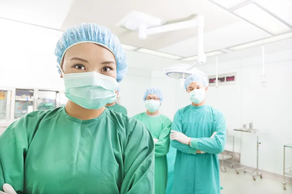 Cirujano sonriente posando con un equipo en una sala quirúrgica — Foto de Stock