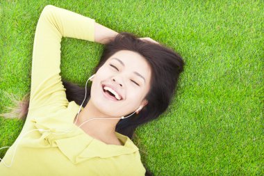 gülümseyen kadın müzik dinleme ve çayır üzerinde yalan