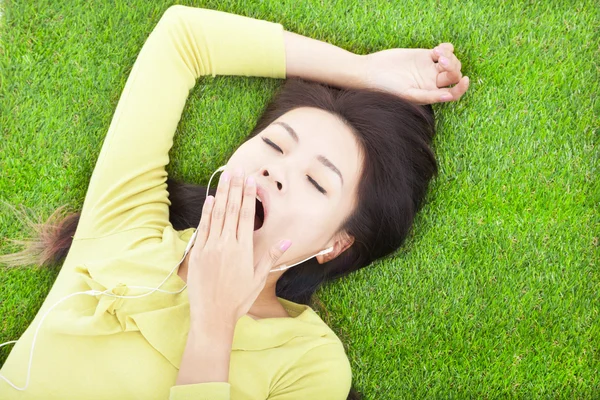 Smiling  woman yawning  and lying on grass — Stock Photo, Image