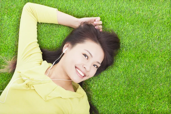 Pretty woman listening music and lying on a meadow — Stock Photo, Image