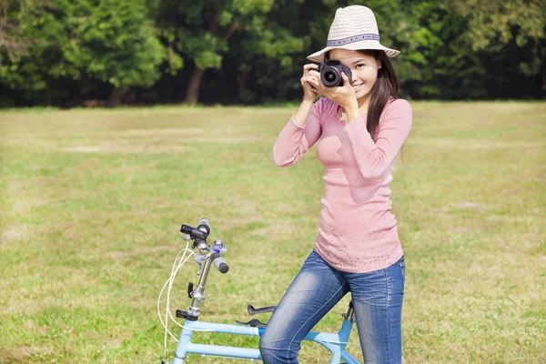 女摄影师拿着相机和坐自行车 — 图库照片