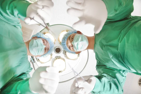 Хірурги та медичний асистент, що працює в операційній кімнаті — стокове фото