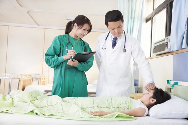 Médecin et assistant examinent la situation de la petite fille fièvre — Photo