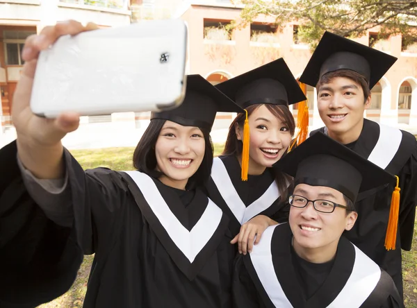 Grupo de graduados tirando fotos com telefone celular — Fotografia de Stock