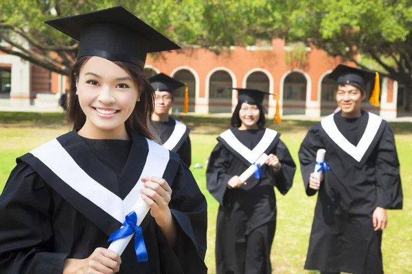 Pretty college graduate holds a diploma with classmates — Stock Photo, Image