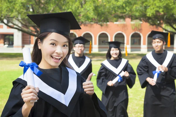 Gülümseyen üniversite mezunu bir diploma ve başparmak kadar tutar — Stok fotoğraf