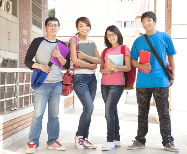Gruppo di studenti in possesso di libri e in piedi a scuola — Foto Stock