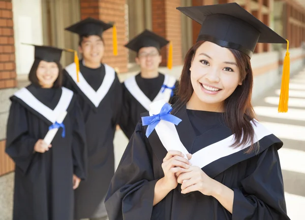 Sorridente faculdade graduação segurando diploma com colegas de classe — Fotografia de Stock