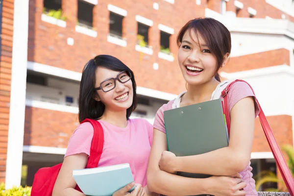 Dos estudiantes sonrientes sosteniendo libros en el campus —  Fotos de Stock