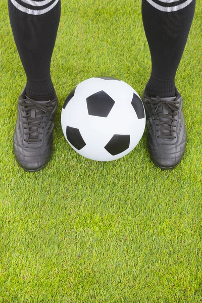 Pés de jogador de futebol e futebol em campo — Fotografia de Stock