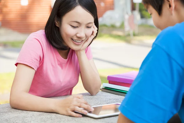 Sourire jeune fille à l'aide d'une tablette avec un ami — Photo