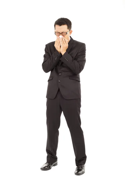 Sick young businessman is sneezing with toilet paper — Stock Photo, Image