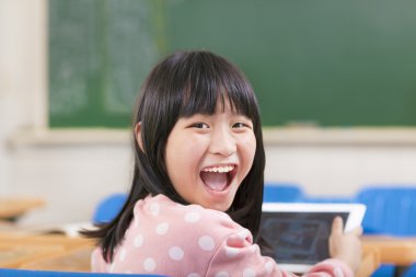 Dijital tablet masa başında tutan mutlu liseli kızlar
