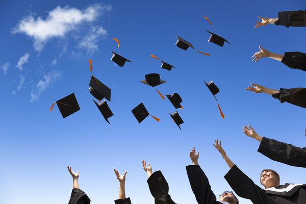 Students throwing graduation hats in the air celebrating