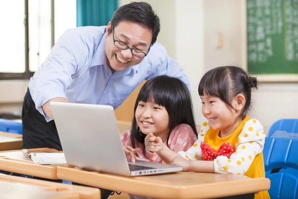 Lärare undervisning barn med en bärbar dator — Stockfoto