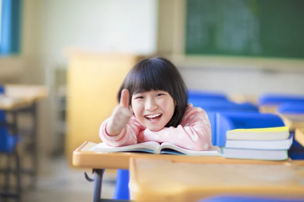 Enfant heureux pouce levé avec livre en classe — Photo