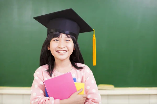 Fille souriante porter un chapeau de graduation et tenant des livres — Photo