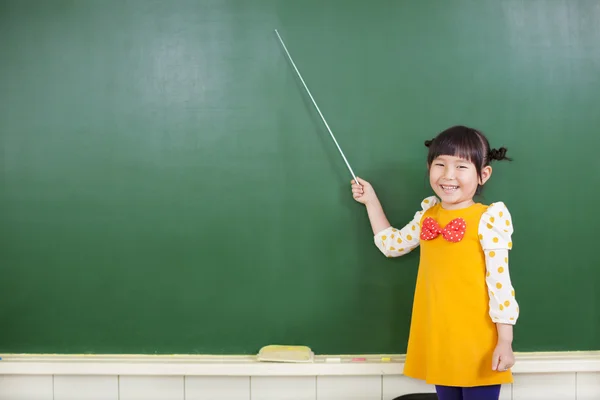 Asiatisches kleines Mädchen zeigt mit einem Schlagstock auf eine Tafel — Stockfoto