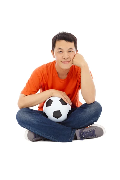 Jovem sentado e segurar um futebol — Fotografia de Stock