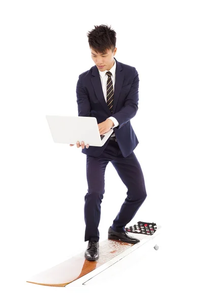 Businessman using a laptop on a  surfboard — Stock Photo, Image