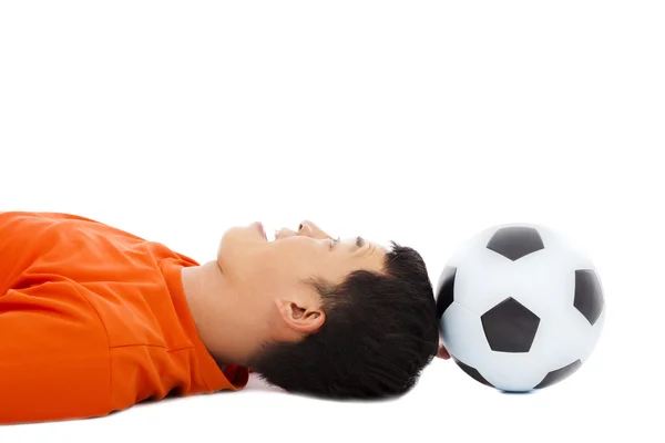 Smiling young man lying down with soccer — Stock Photo, Image