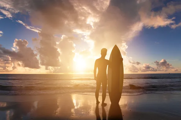 Man die op een strand met zonsondergang achtergrond surfen — Stockfoto