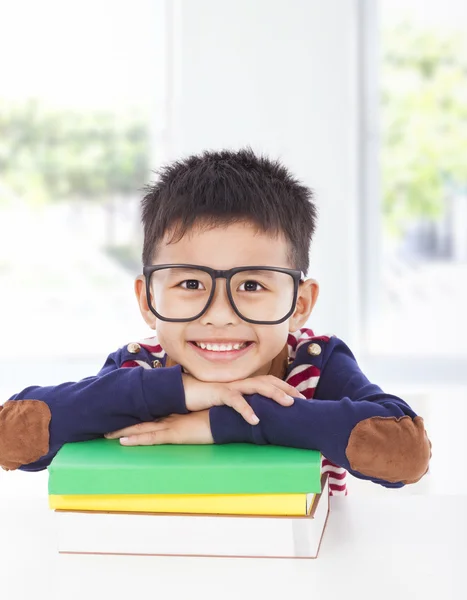 Niño sonriente acostado en los libros — Foto de Stock