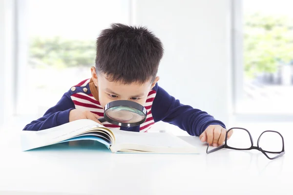 Маленький мальчик-детектив ищет подсказки из книг — стоковое фото