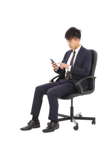 Jovem empresário tocando telefone inteligente na cadeira — Fotografia de Stock