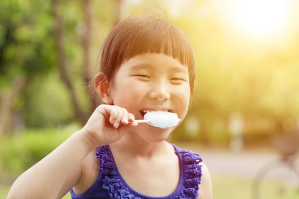 Happy little girl eating popsicle with sunset background — Stock Photo, Image