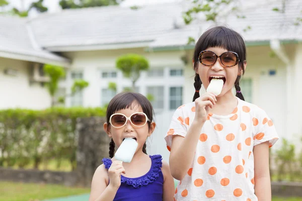 Mignonnes petites filles manger de la crème glacée avant leur maison — Photo