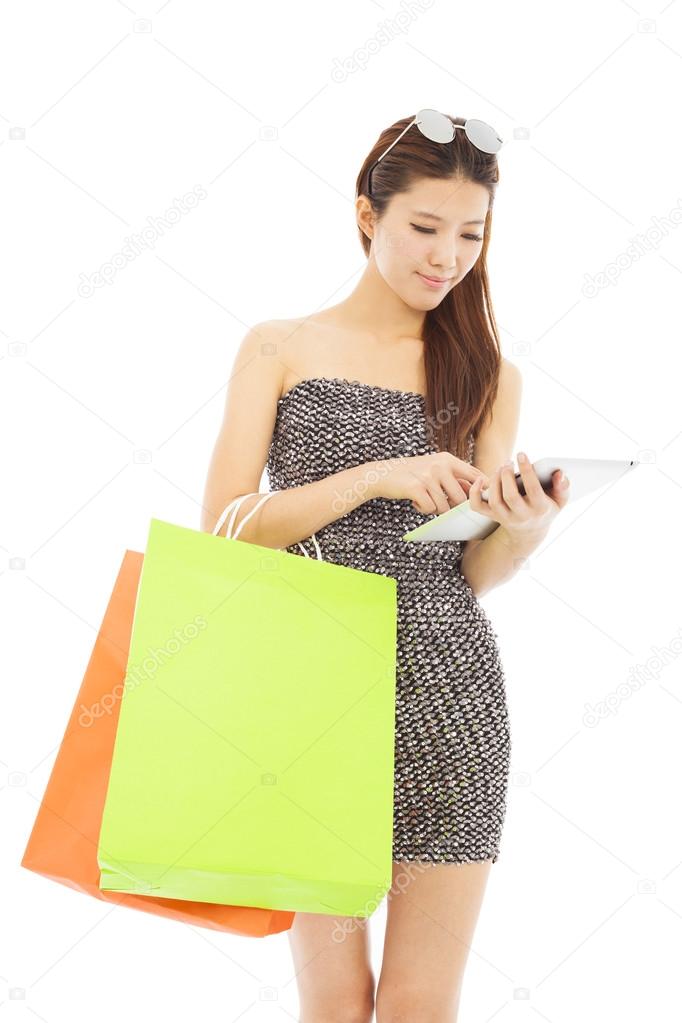  young  woman holding shopping bags and using  the tablet