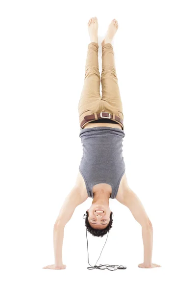 Young man doing a handstand against and listening music — Stock Photo, Image