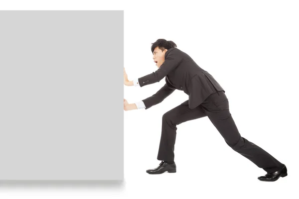 Jovem empresário empurrando uma placa em branco no fundo branco — Fotografia de Stock