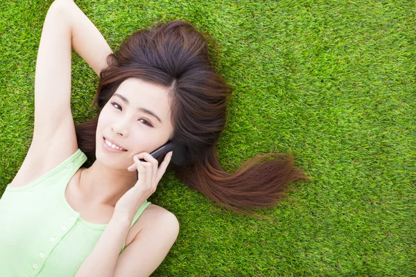 Lachende meisje liggen op een weide en spreken door smartphone — Stockfoto