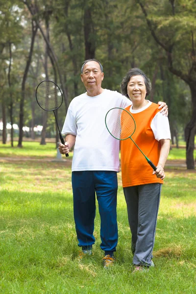 Smiling older sibling and sister holding badminton racket — Stock Photo, Image