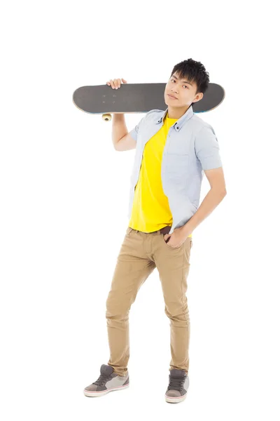 Уверенный молодой человек, стоящий и держащий скейтборд — стоковое фото