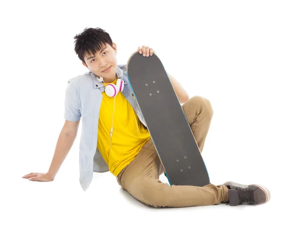 Cooler Mann sitzt und hält ein Skateboard — Stockfoto