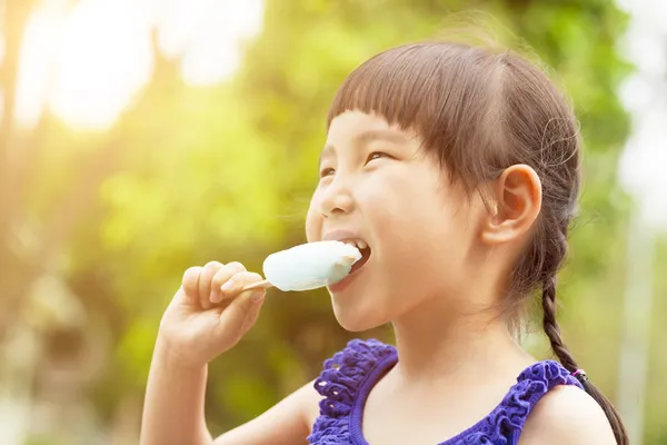 Niña feliz comiendo paleta en verano con puesta de sol —  Fotos de Stock