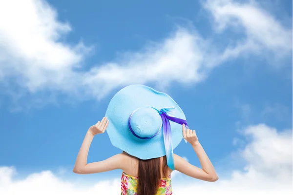 Parte de trás da menina segurando um chapéu com fundo azul céu — Fotografia de Stock