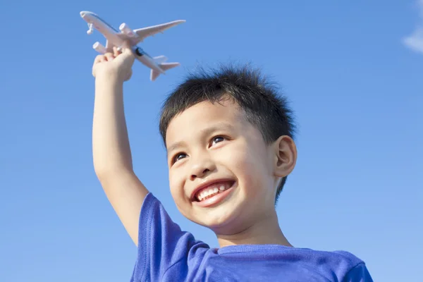 Счастливый мальчик играет в самолетную игрушку на голубом фоне неба — стоковое фото