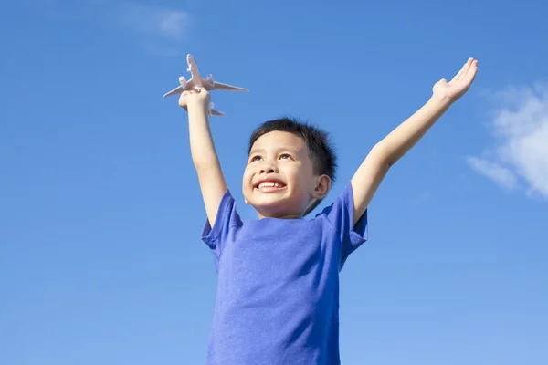 Joyful little boy holding a toy with blue sky background — Stock Photo, Image