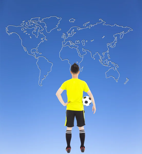 Futbolista sosteniendo un fútbol y mirando mapa global — Foto de Stock