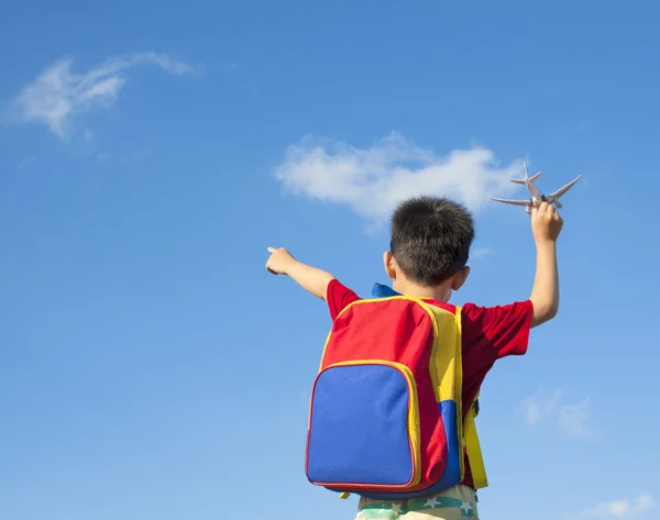 Kleiner Junge hält ein Flugzeugspielzeug in der Hand und zeigt in den Himmel — Stockfoto