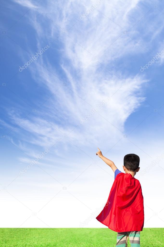 happy little boy wore superhero suit and point to sky